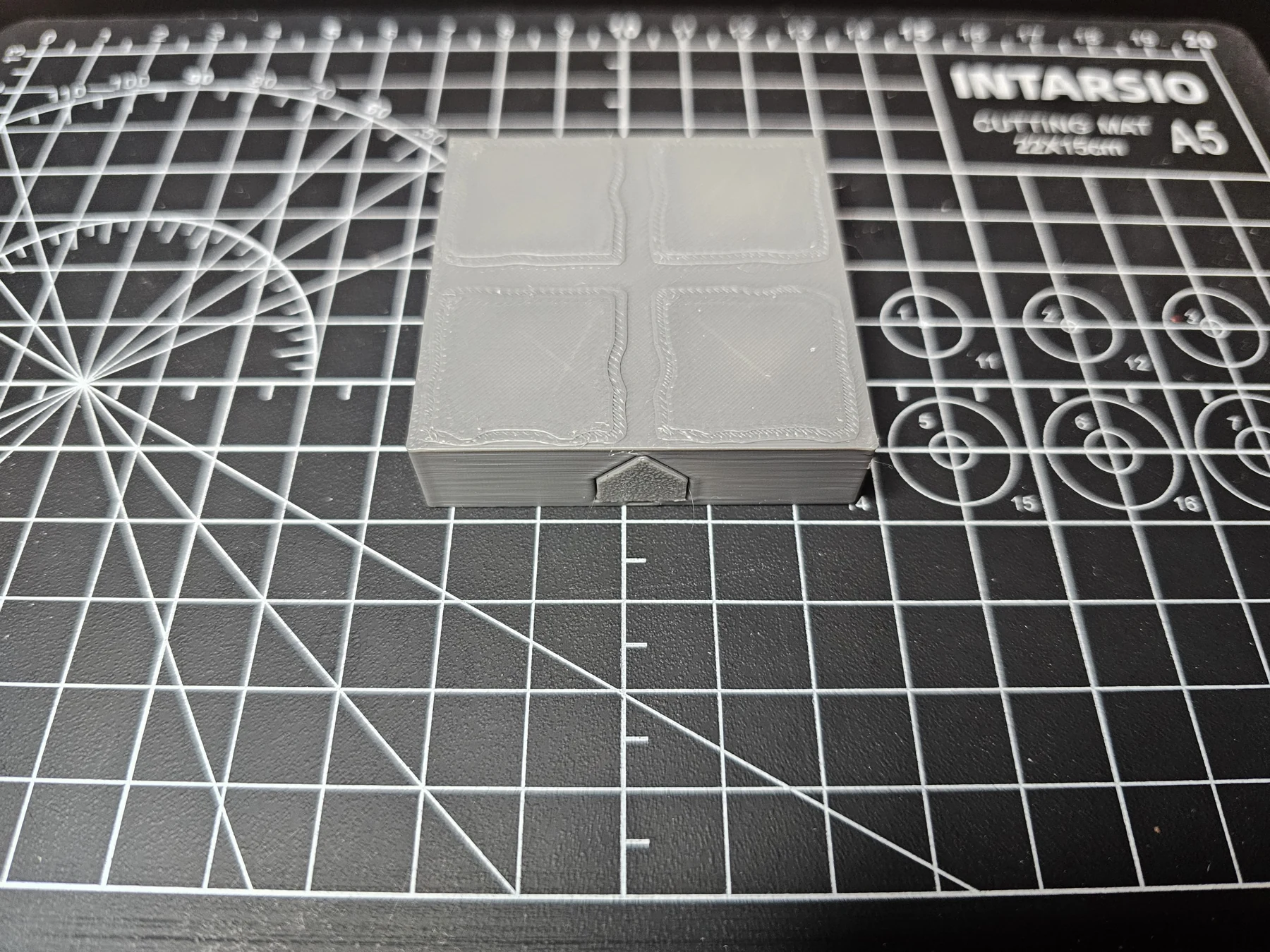Photograph of a real printed gray stone modular dungeon floor tile